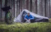 Man camping in the woods beside tent and bike